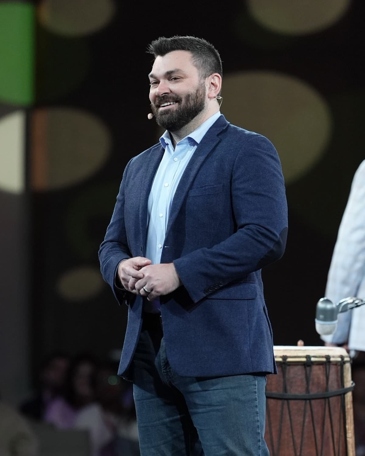 Clif Mathews speaking on stage with an over-ear microphone